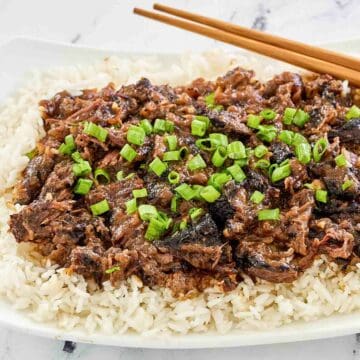 Asian beef short ribs over rice on a platter.