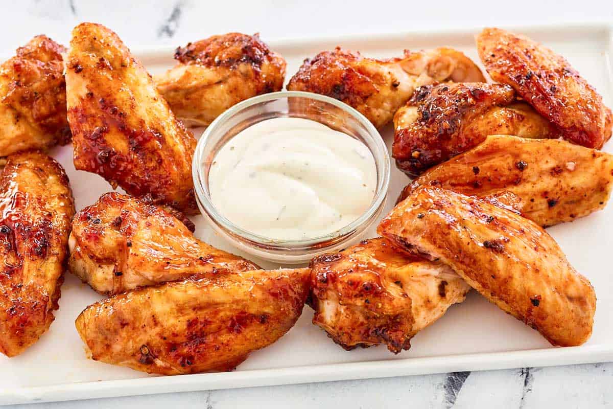 baked barbecue chicken wings and ranch sauce on a platter.
