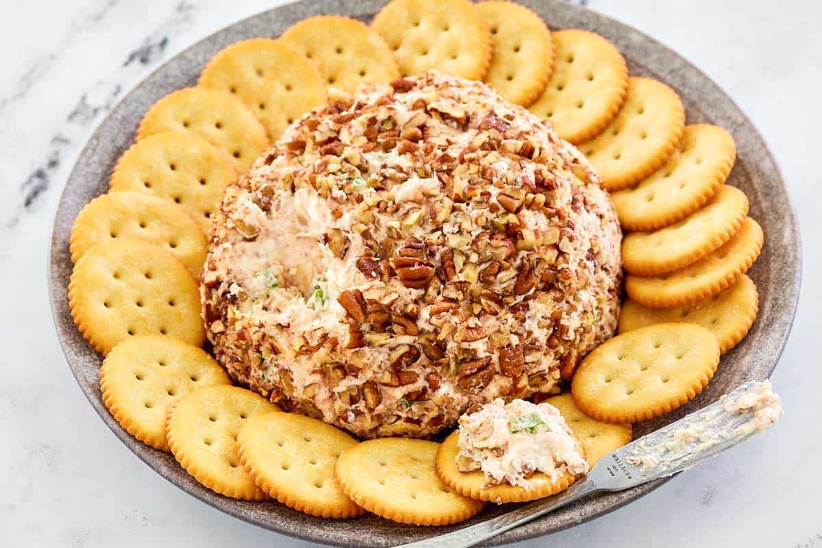 deviled ham cheese with pecans and crackers on a platter.