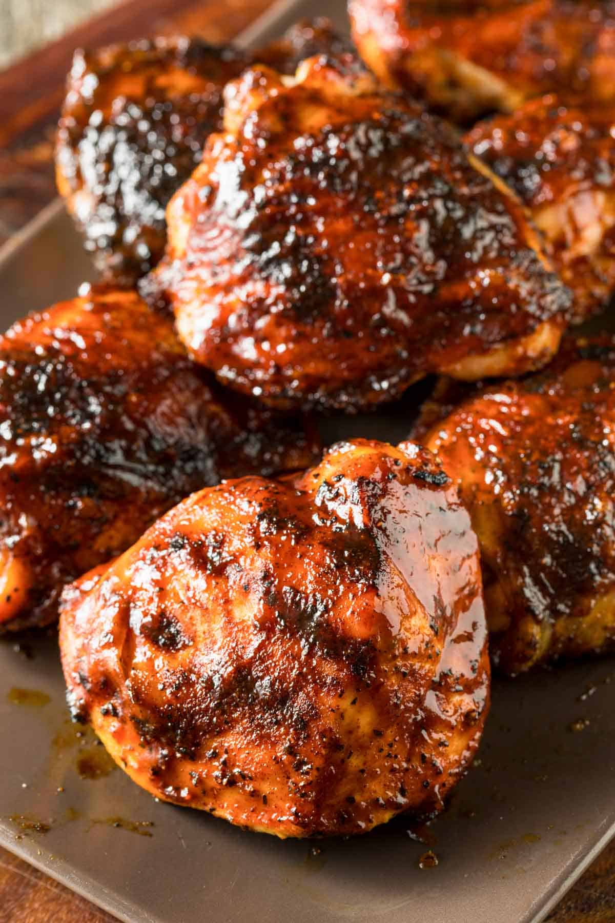 grilled bbq chicken thighs stacked on a platter.