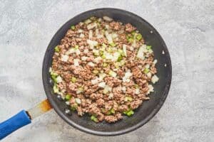 browned ground beef, onions, and bell peppers in a skillet.