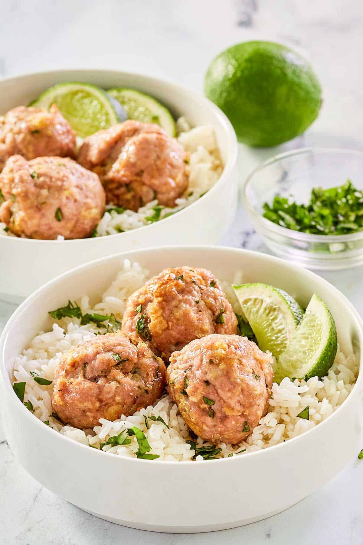 Asian pork meatballs over rice in bowls.