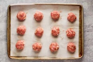 raw meatballs on a baking sheet.