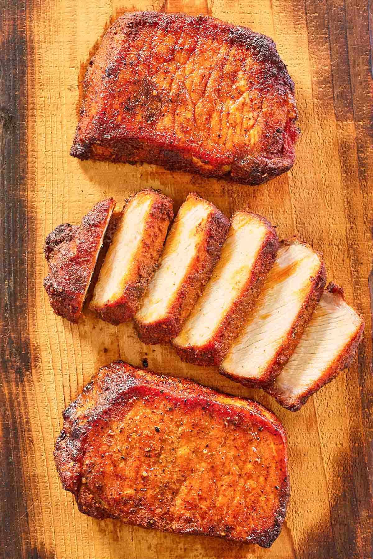 overhead view of smoked pork chops on a wood board.