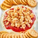 layered shrimp dip and round butter crackers on a platter.