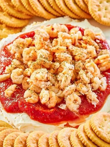 layered shrimp dip and round butter crackers on a platter.