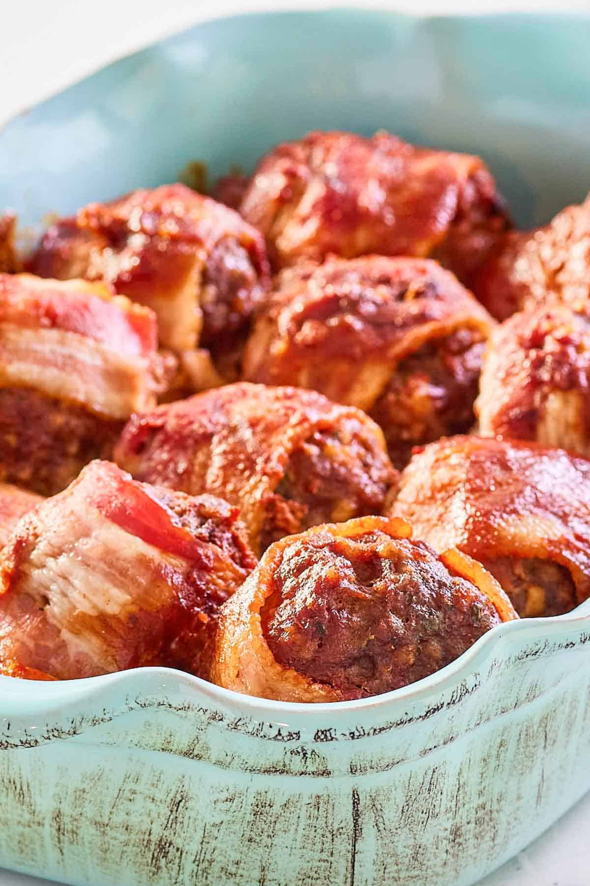 Bacon-wrapped smoked meatballs with BBQ sauce in a blue serving dish.