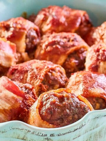 Bacon wrapped smoked meatballs with BBQ sauce in a serving dish.