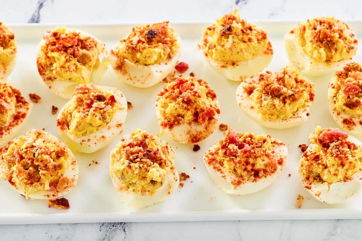 Bacon ranch deviled eggs with cheddar cheese on a platter.