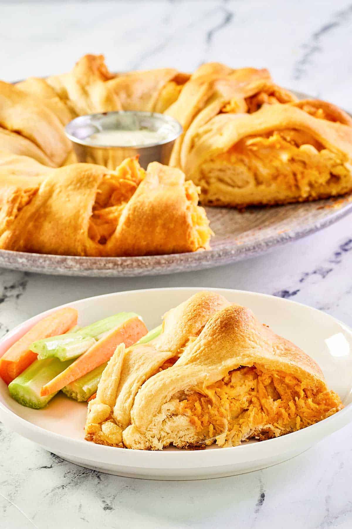 Buffalo chicken crescent ring serving on a plate with the ring behind it.