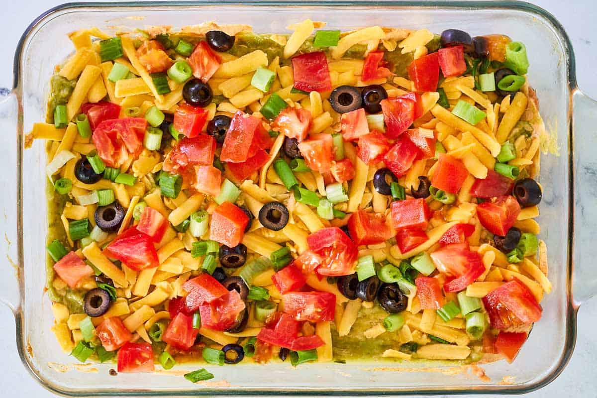 Layered taco dip with refried beans in a glass dish.