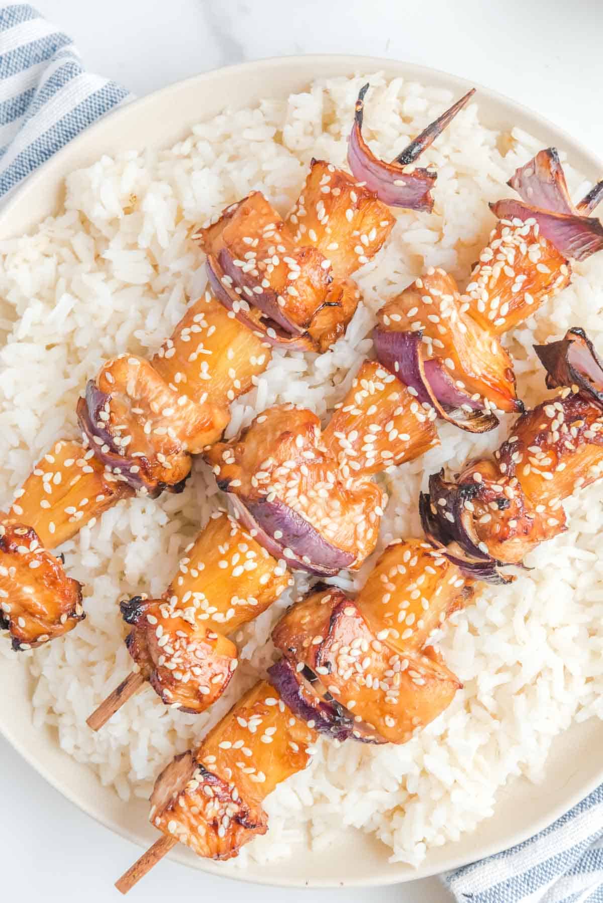 Air fryer Hawaiian teriyaki chicken kabobs over rice on a plate.