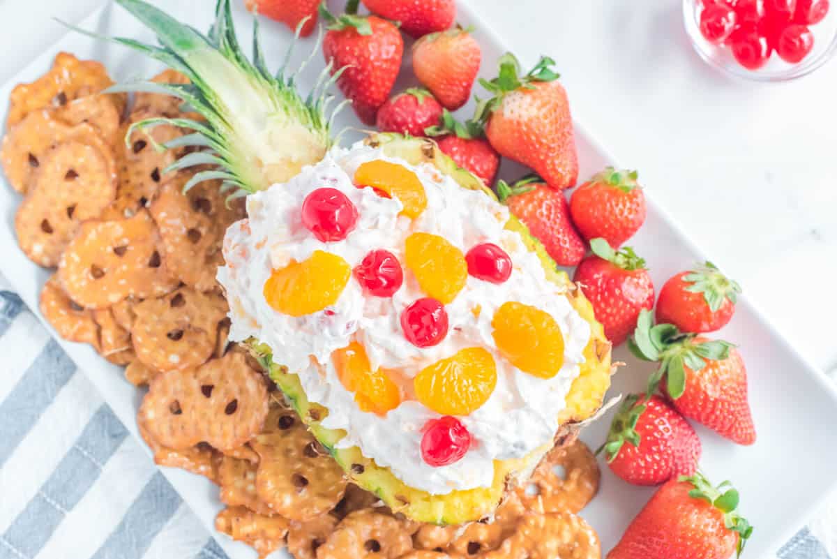 Pina colada fruit dip in a pineapple topped with cherries and mandarin oranges.
