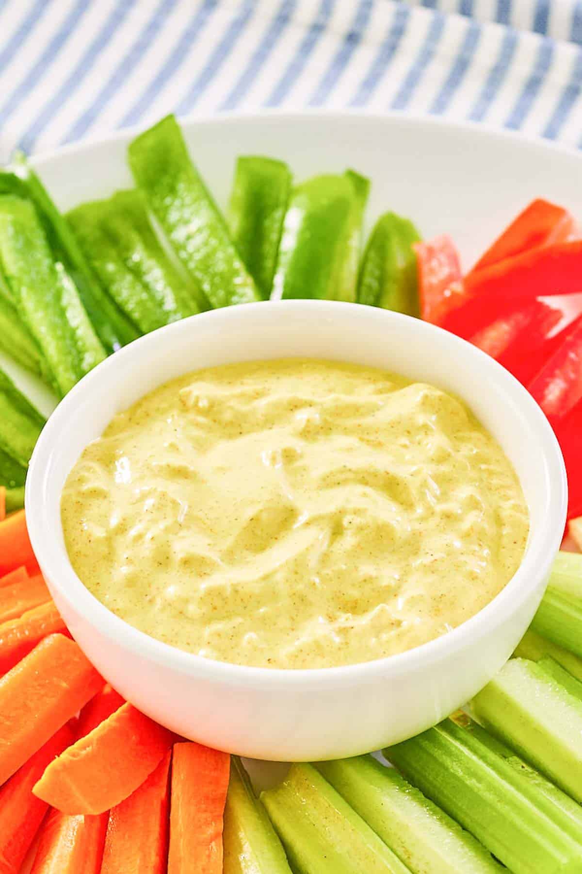 Curry dip in a bowl and vegetables around it on a platter.