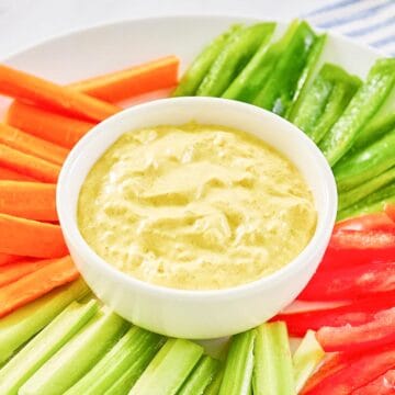 Curry dip in a small bowl and vegetables around it.