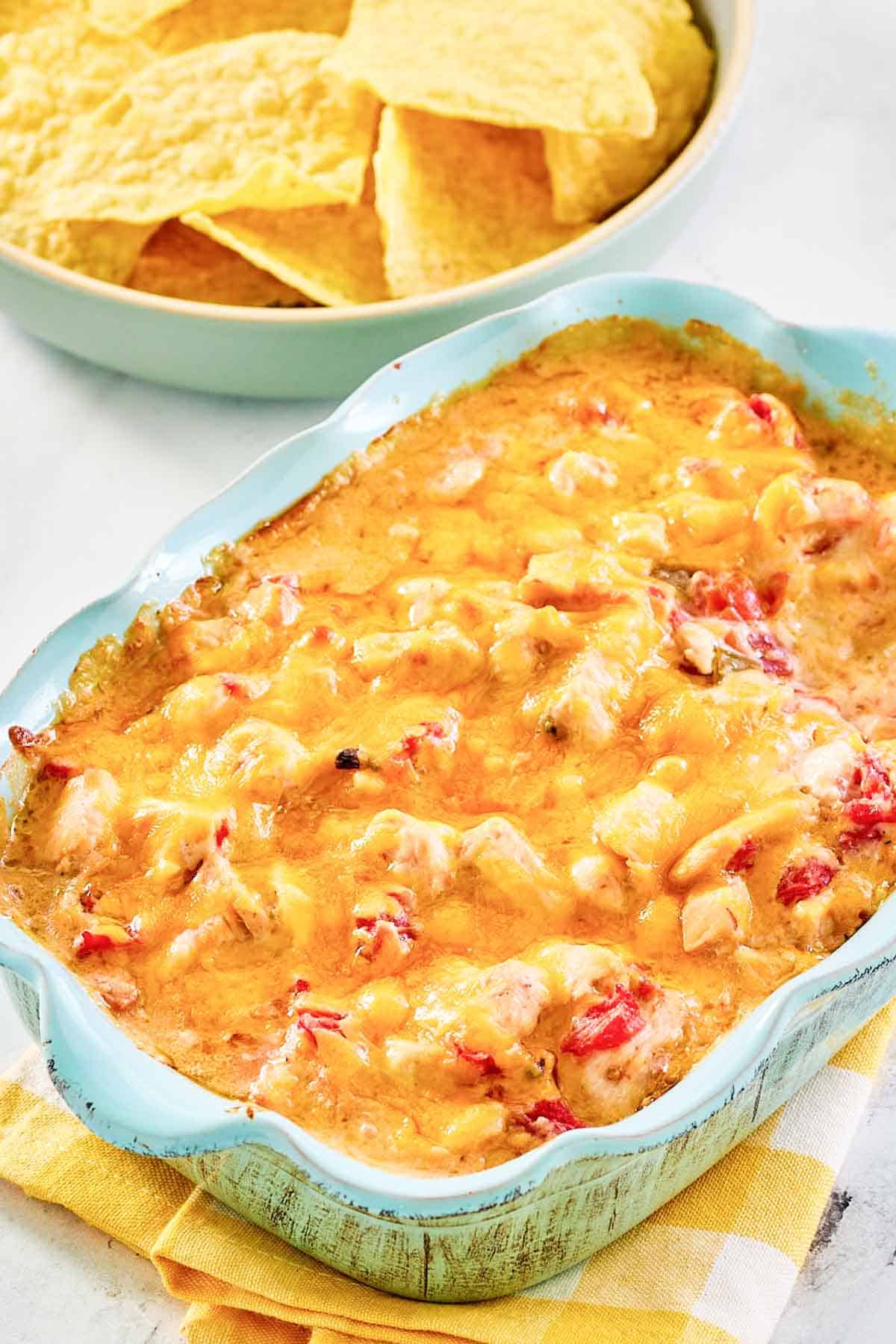 Chicken rotel dip in a baking dish and a bowl of tortilla chips.