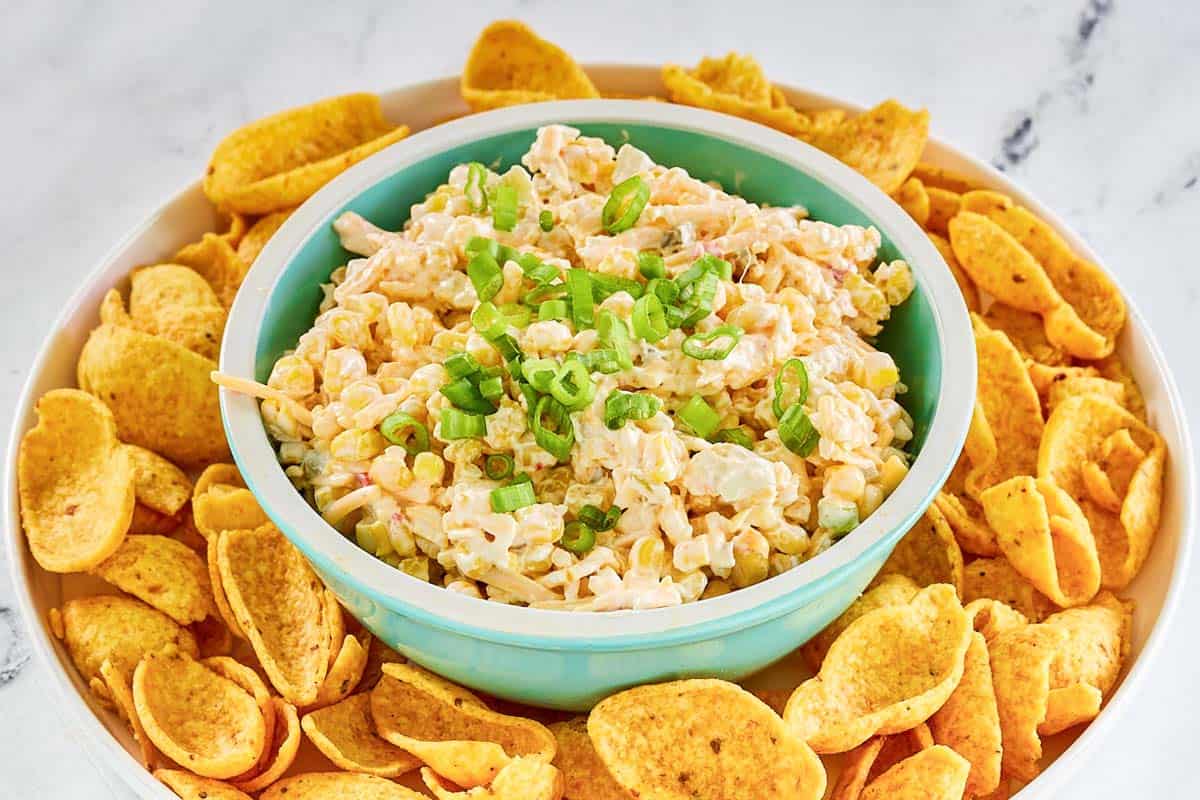 A bowl of corn chip dip and Fritos corn chips on a platter.