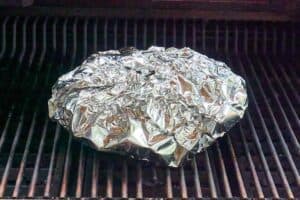 Pork wrapped in foil in a smoker.