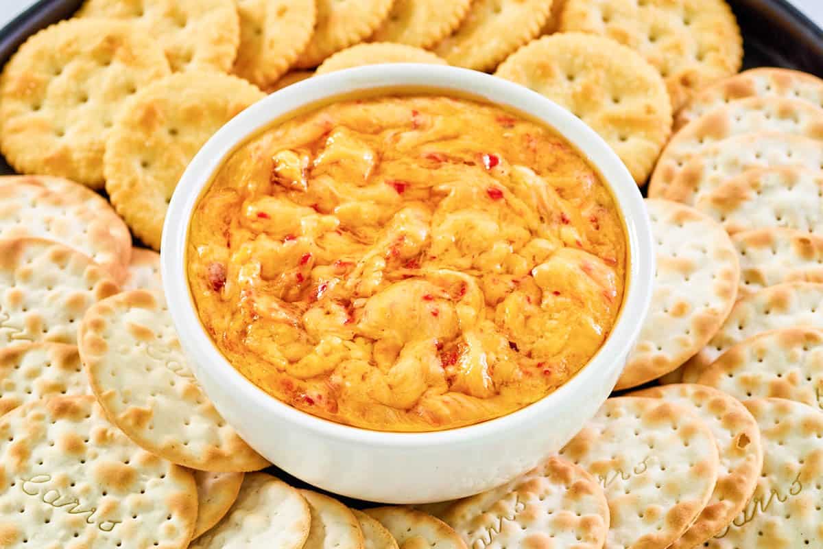 Hot pimento cheese dip with crackers on a platter.