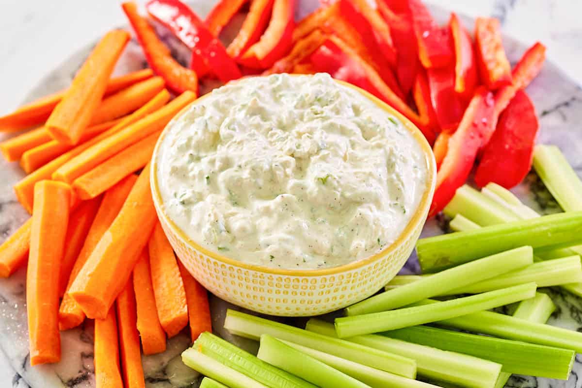 Homemade green onion dip in a bowl and fresh veggies around it.
