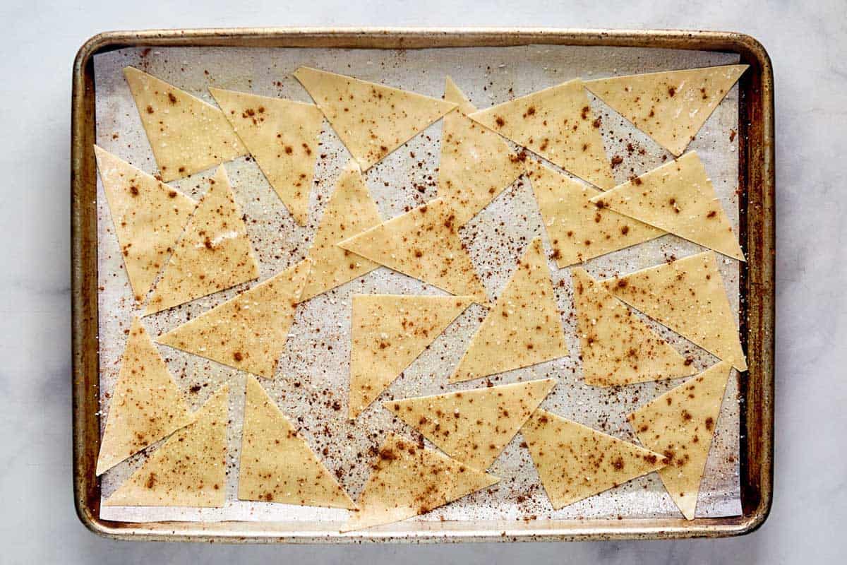 Seasoned wonton wrappers on a baking sheet.