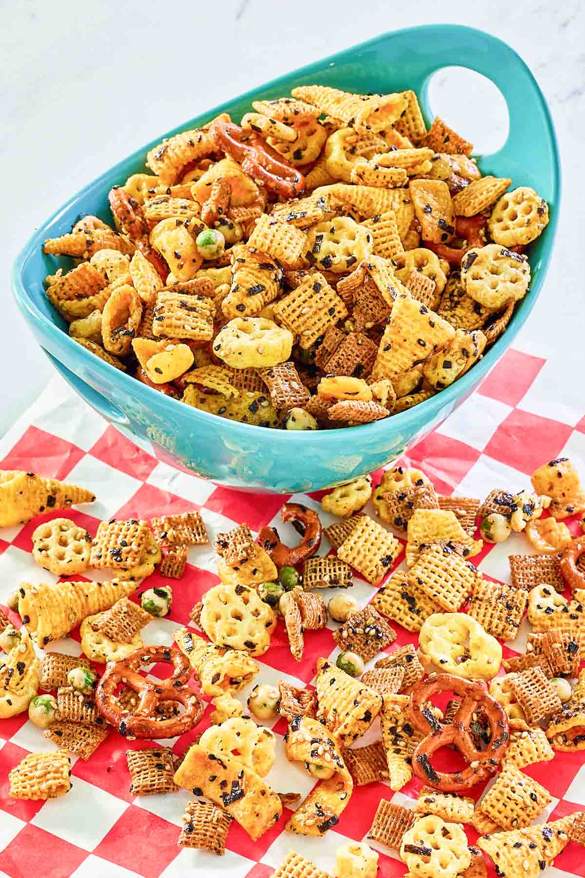 Homemade Furikake Chex Mix in a serving bowl and scattered on parchment paper.