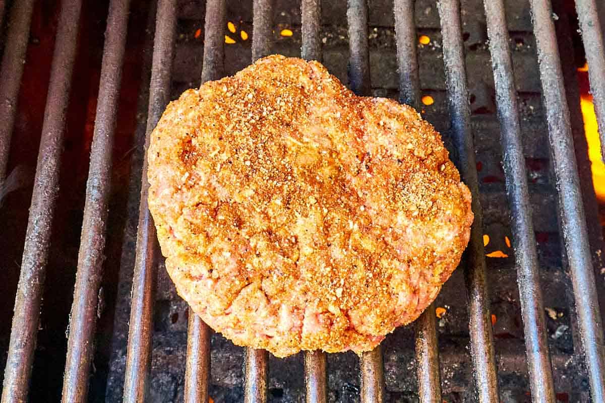 Seasoned burger patty on a grill.