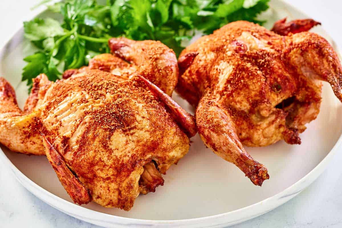 Seasoned and smoked cornish hens on a platter.