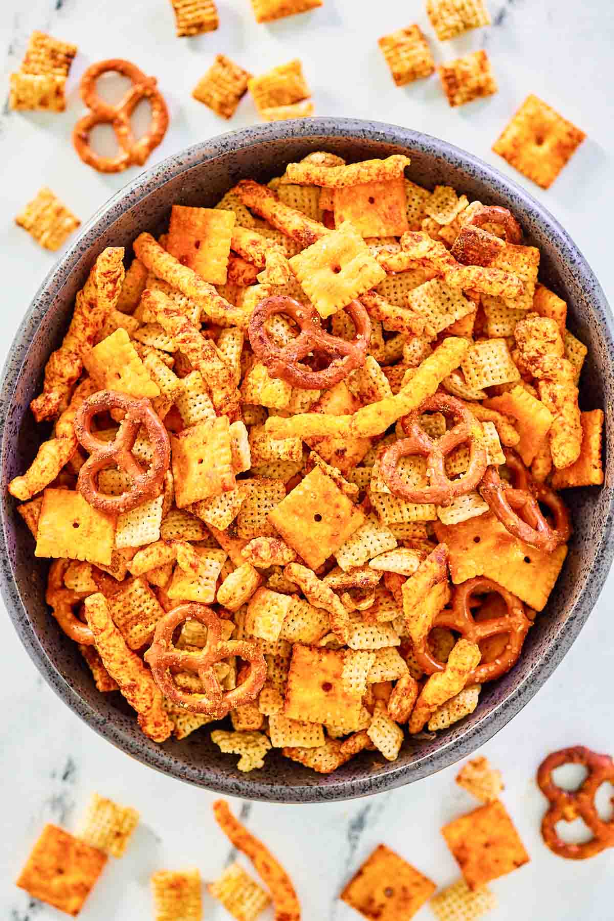 Homemade Cheddar Chex Mix in and scattered around a bowl.