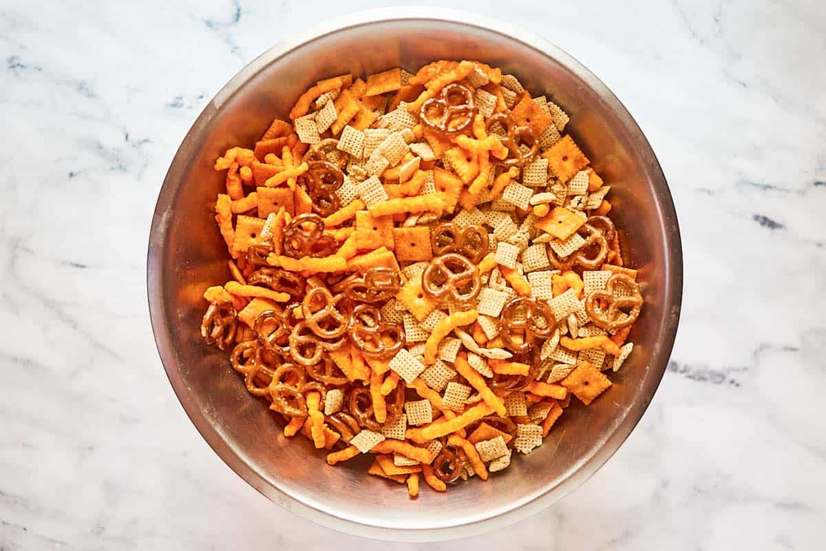 Chex cereals, pretzels, cheese crackers, and Cheetos in a bowl.