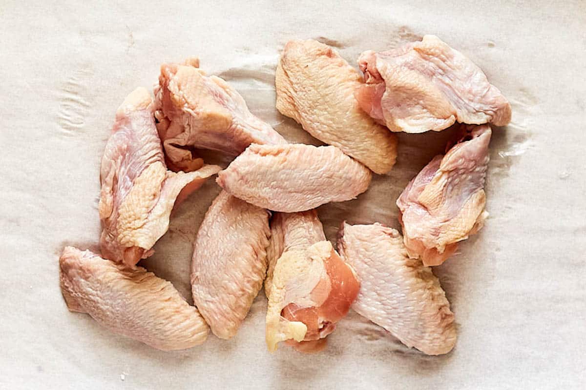 Raw chicken wings on parchment paper.