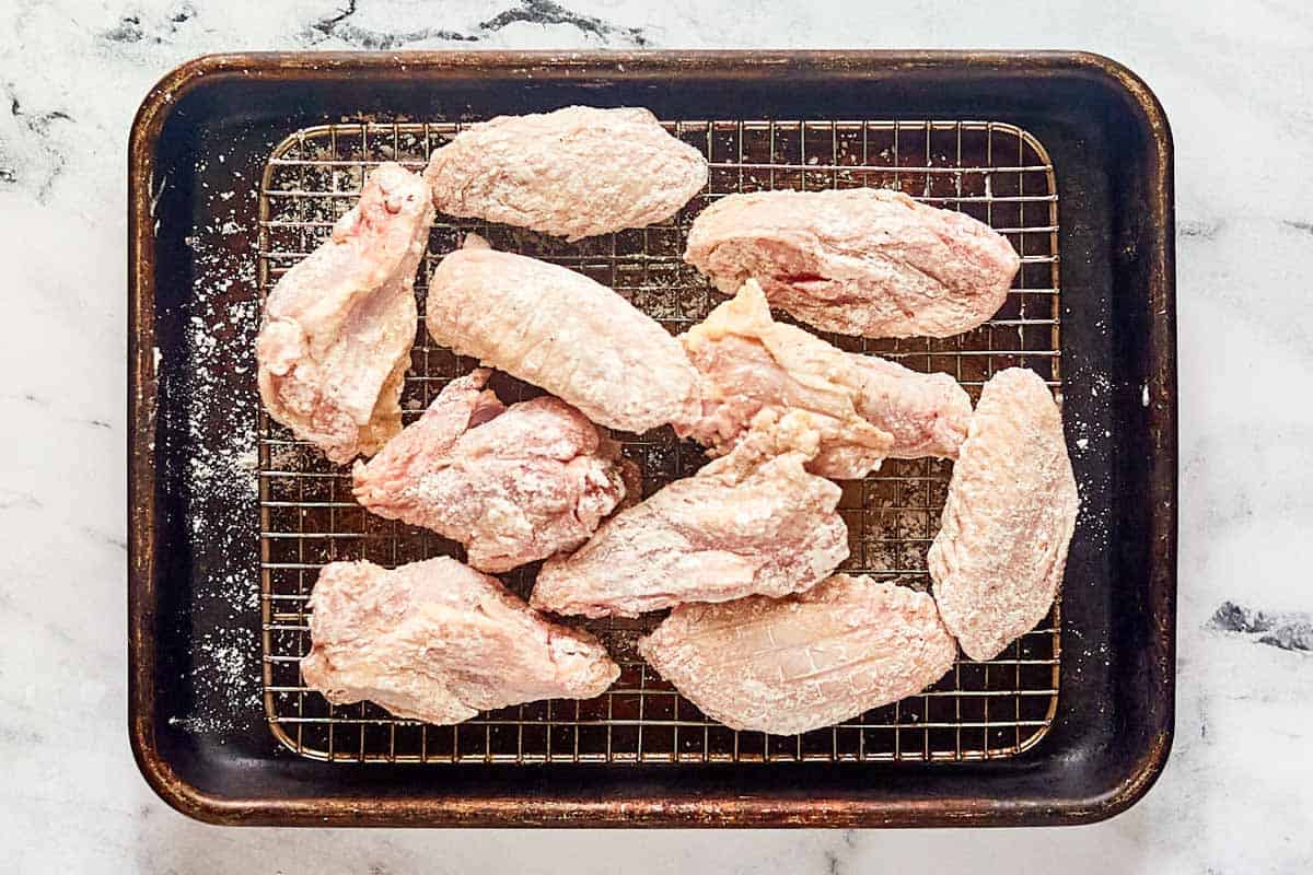 Seasoned flour breaded chicken wings on a wire rack.