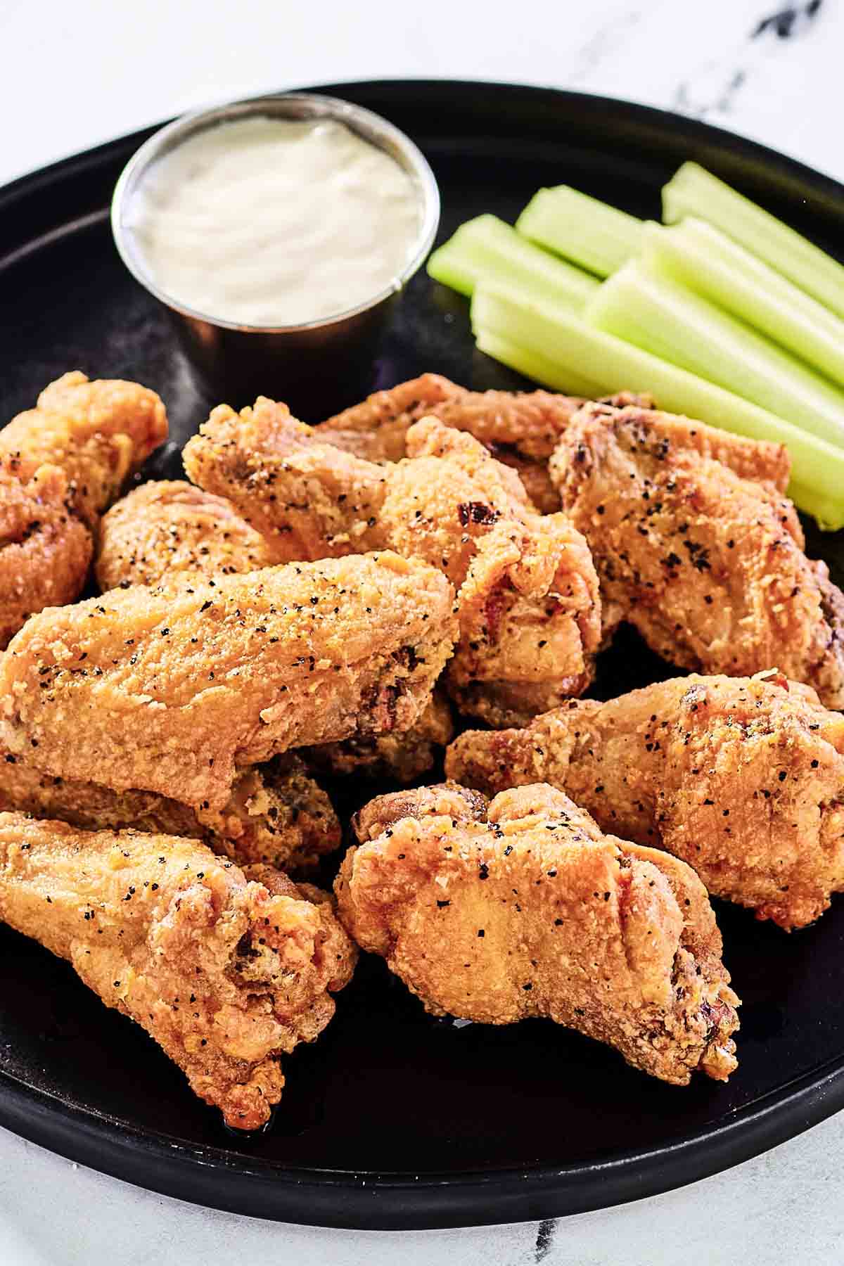 Breaded lemon pepper wings, dipping sauce, and celery sticks on a plate.