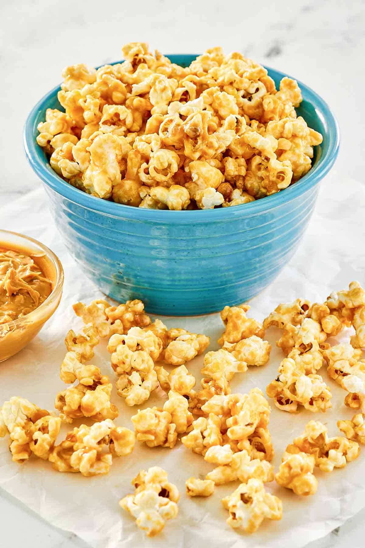 Homemade peanut butter popcorn on parchment paper and in a bowl.