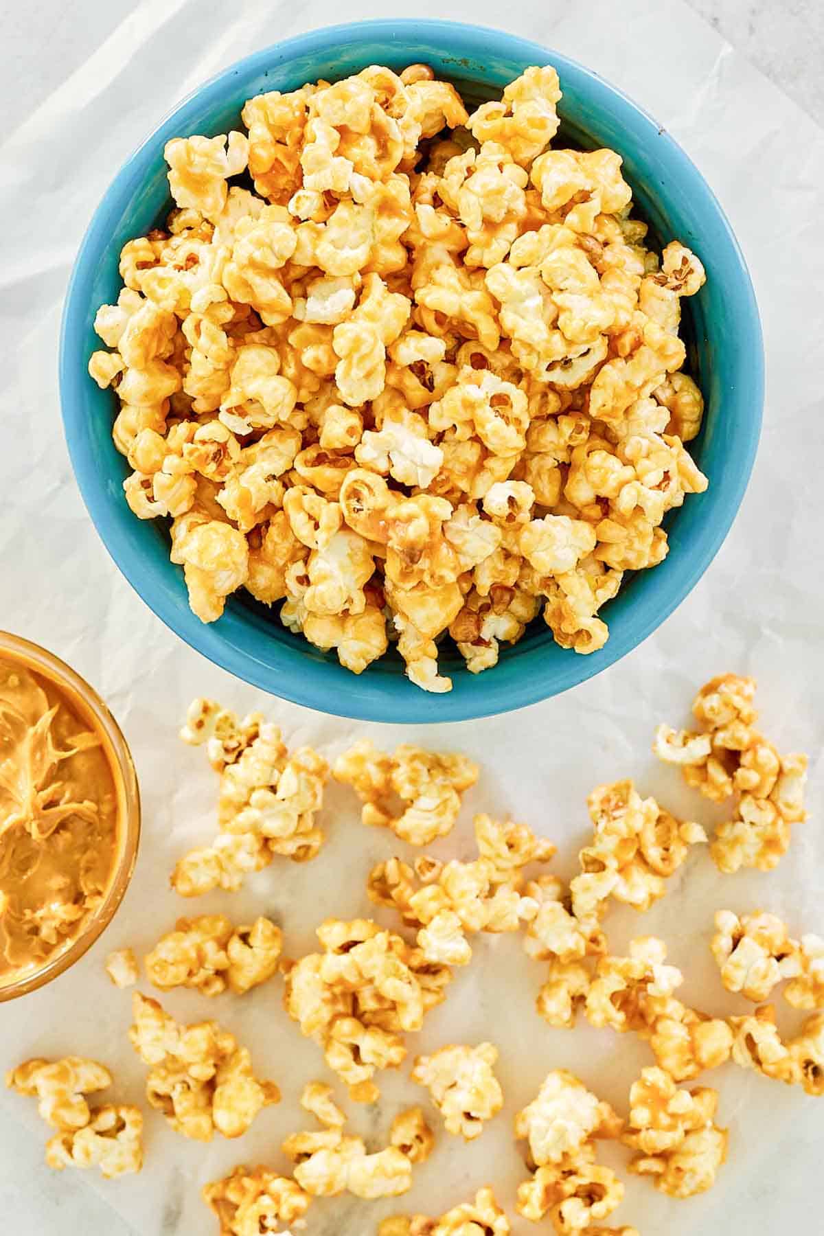 Homemade peanut butter popcorn in a bowl and scattered on parchment paper.