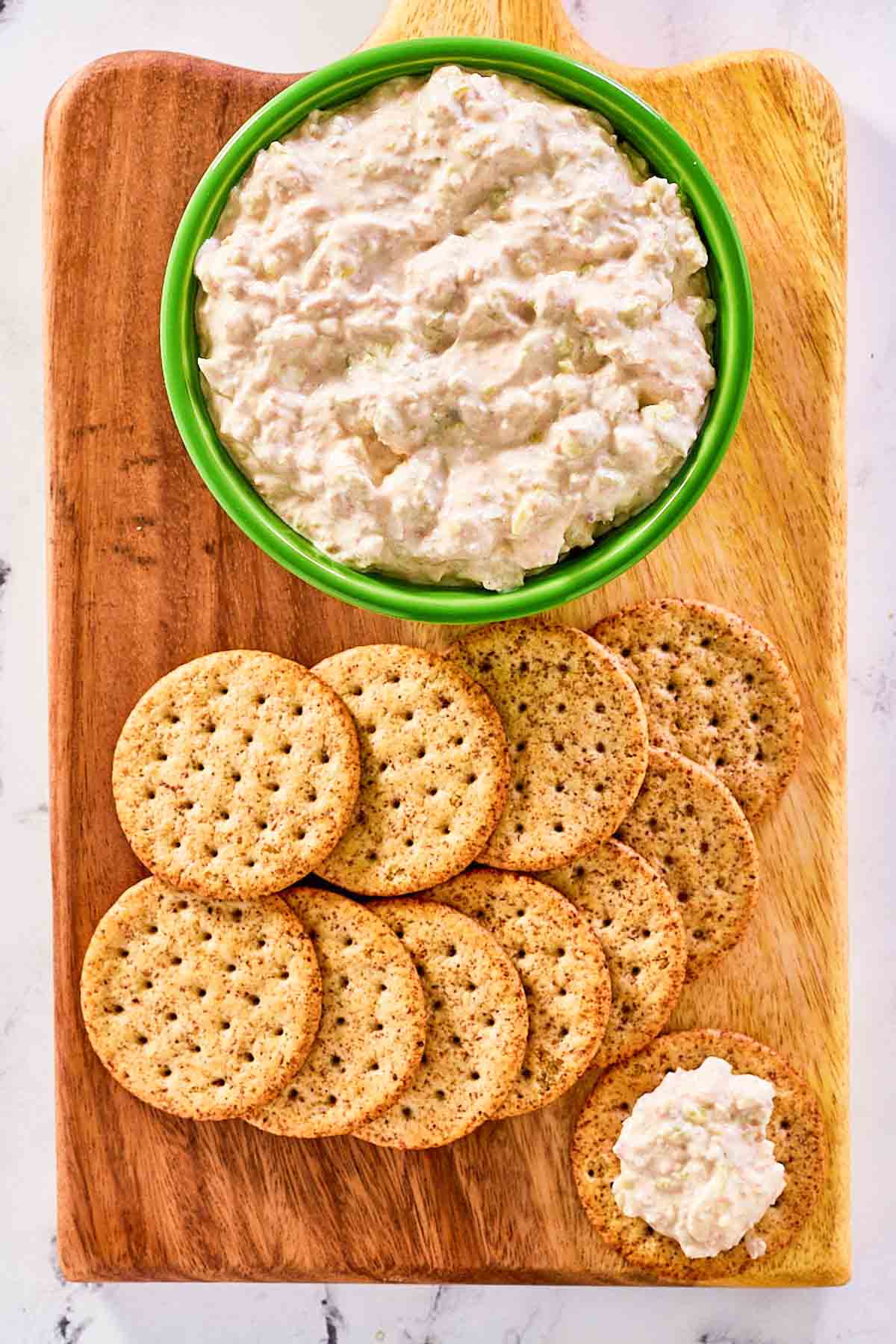 Pepperoncini dip and crackers on a wood serving board.