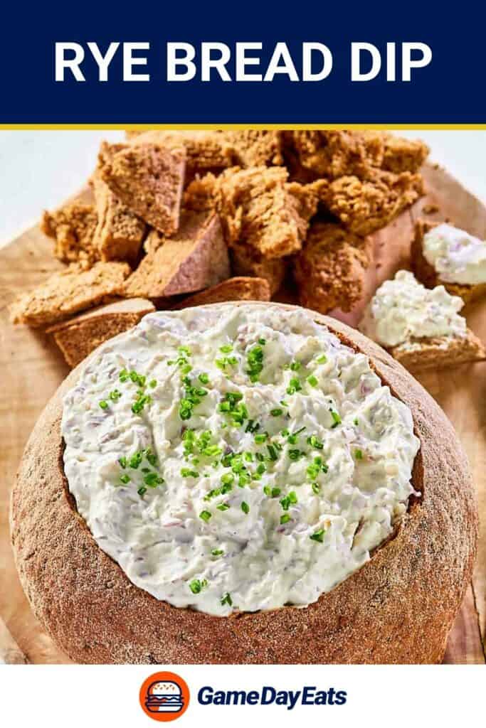 Rye bread dip in a rye bread bowl and pieces of rye bread behind it.