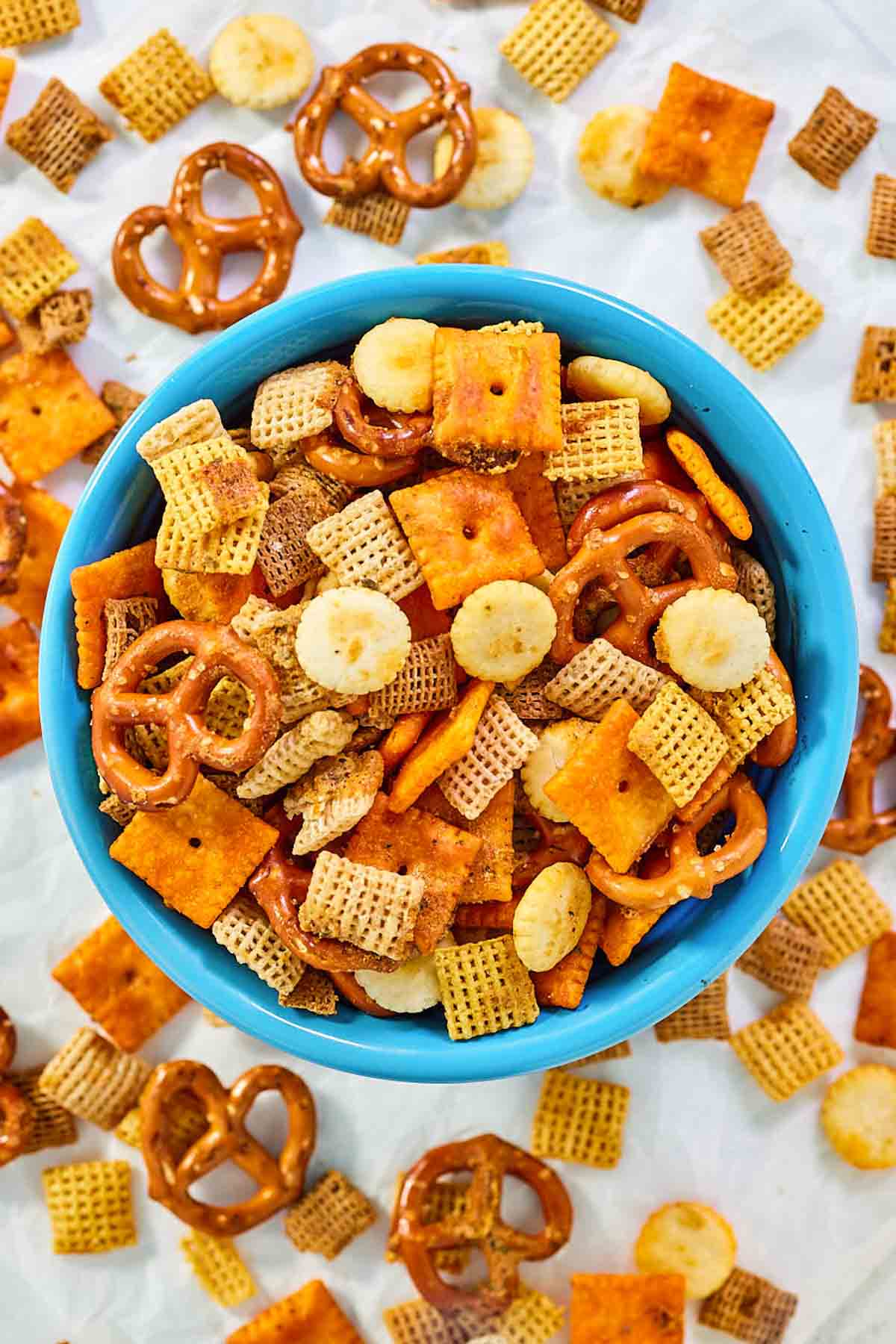 Homemade cheesy ranch chex mix in a bowl and scattered around it.