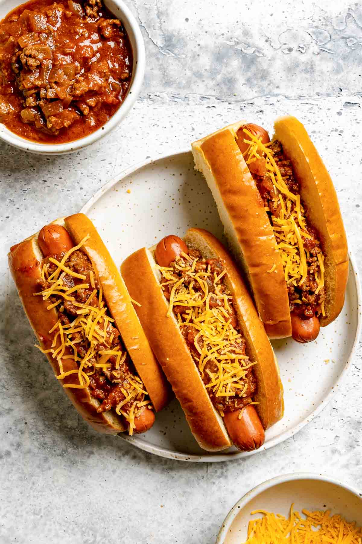 Homemade hot dog chili in a bowl and on hot dogs.