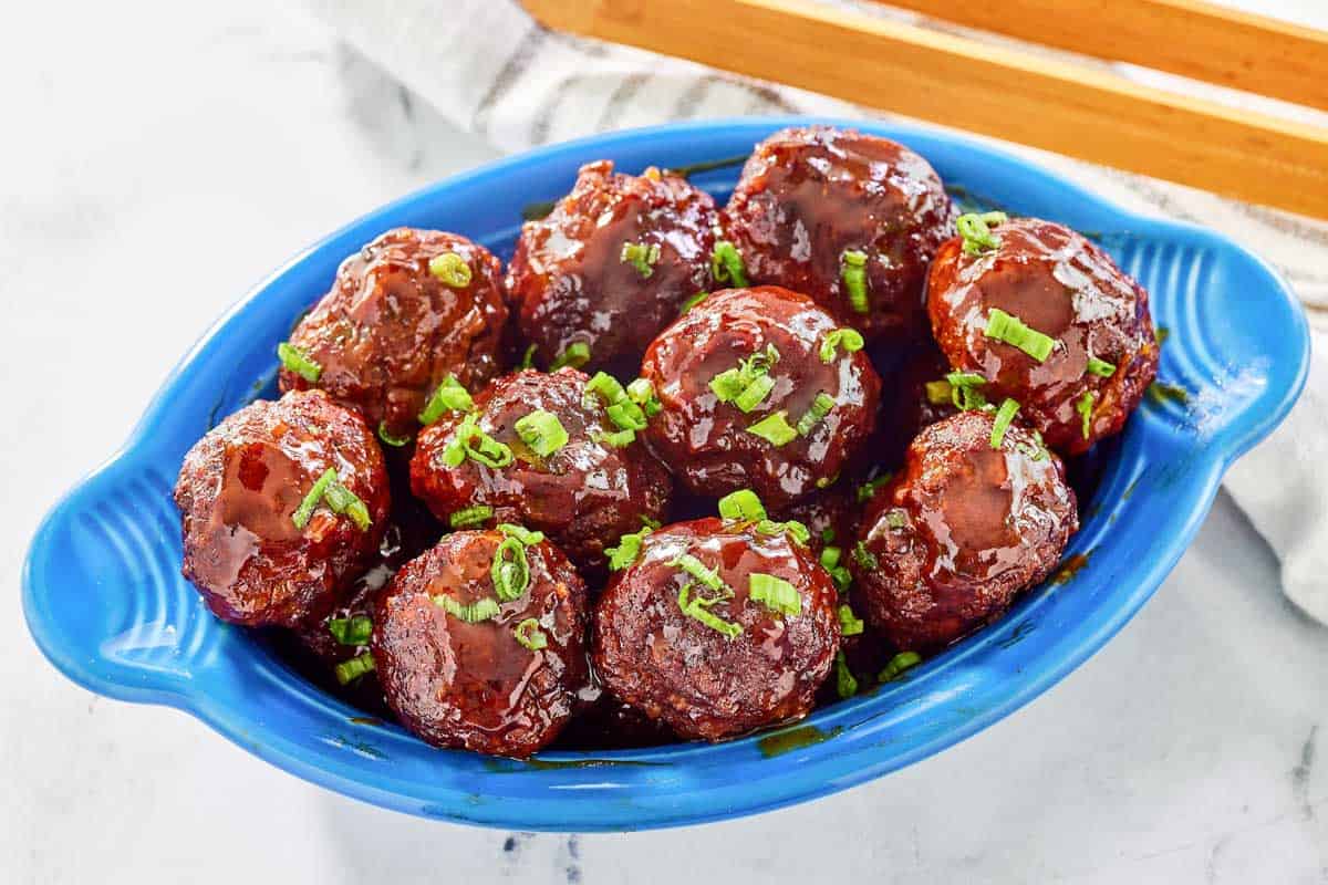 BBQ meatballs in a dish on a marble surface.