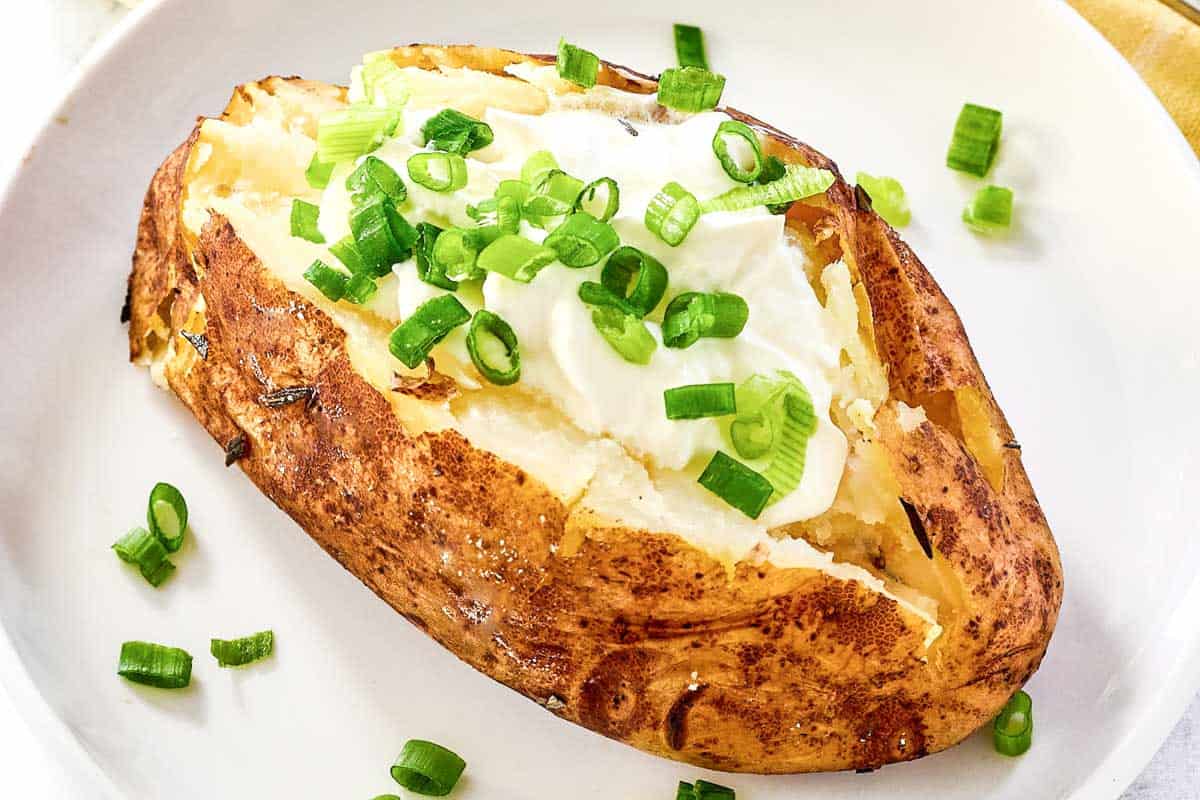 Grilled baked potato topped with butter, sour cream, and chives.