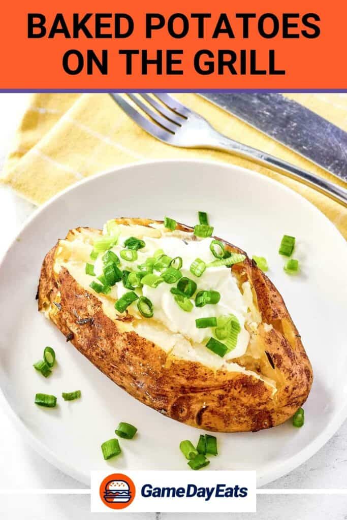Grilled baked potato on a plate and a knife and fork beside it.