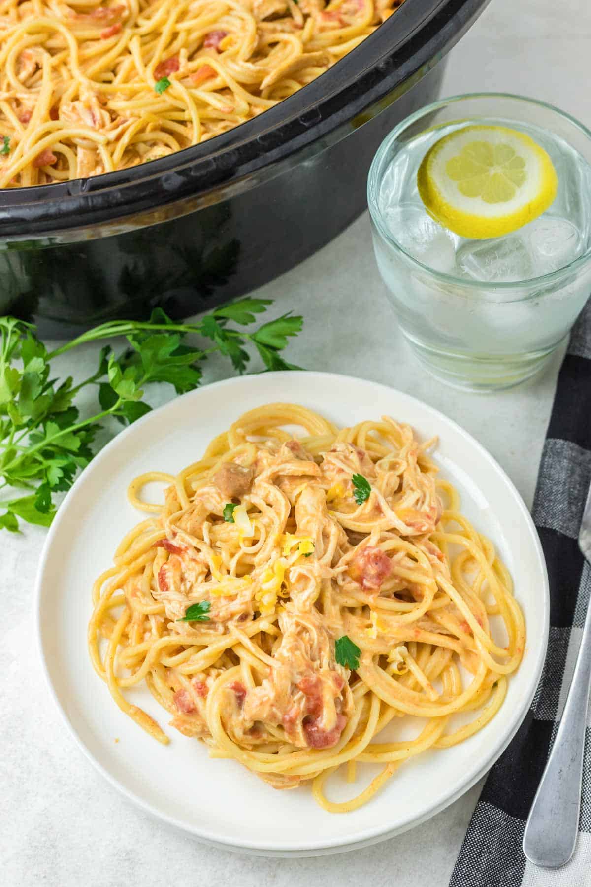 Chicken spaghetti in a crockpot and on a plate.