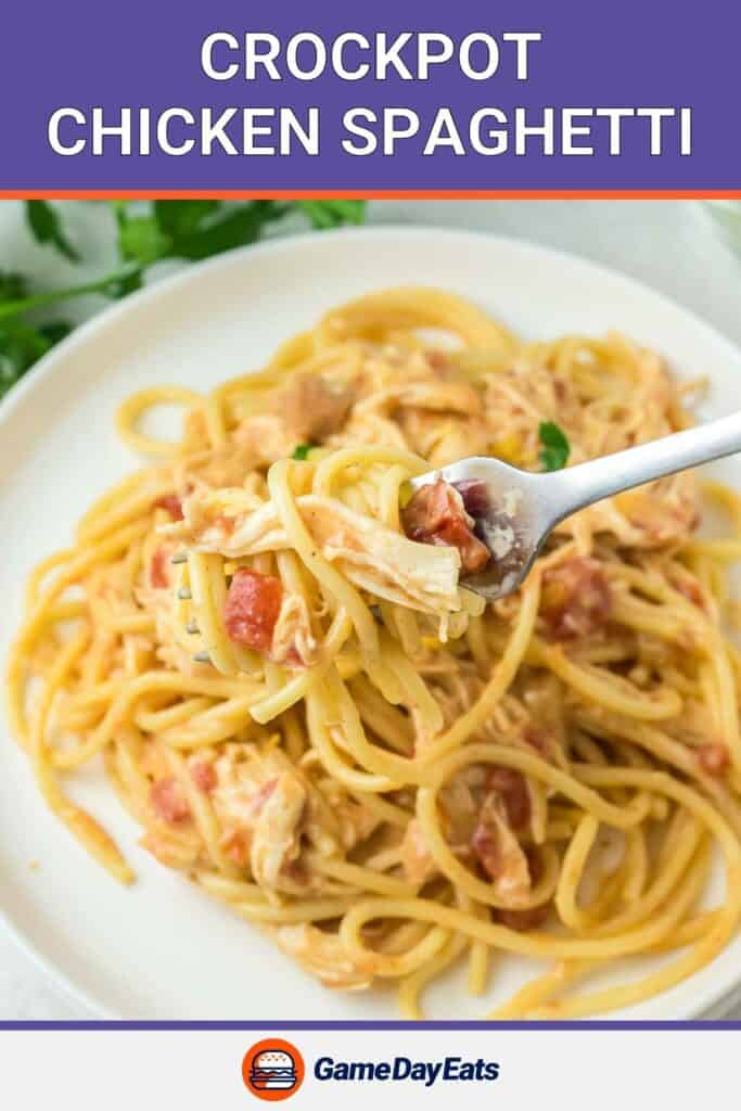 Crockpot chicken spaghetti on a fork over a plate of it.